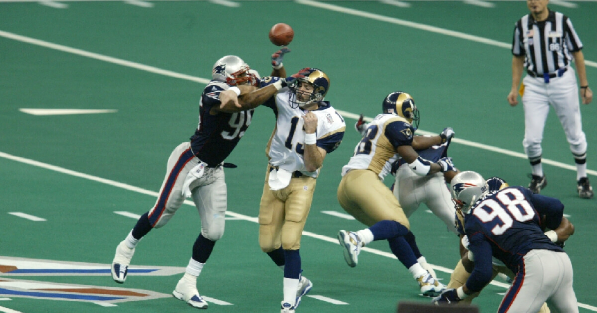 Roman Phifer #95 of the New England Patriots breaks a pass by quarterback Kurt Warner #13 of the St.Louis Rams during Superbowl XXXVI at the Superdome in New Orleans, Louisiana. The Patriots defeated the Rams 20-17.