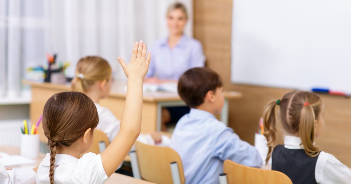 Student raising her hand in a classroom.