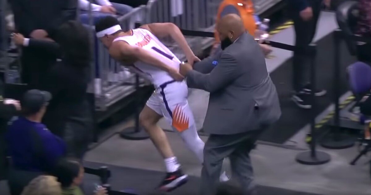A security guard at Talking Stick Resort Arena tries to restrain the Phoenix Suns' Devin Booker.