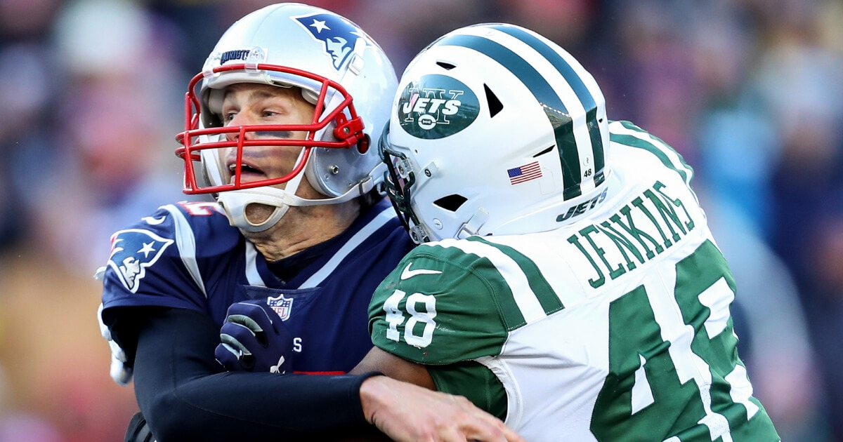 Tom Brady of the New England Patriots is tackled by Jordan Jenkins of the New York Jets during Sunday's game at Gillette Stadium.