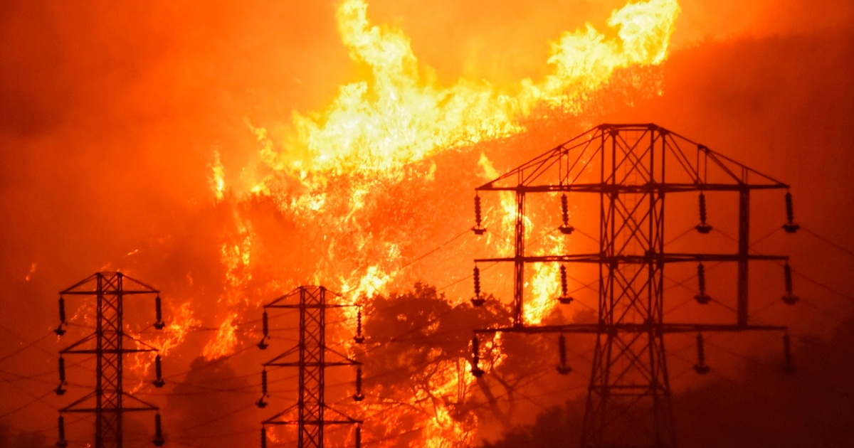 In this Dec. 16, 2017, file photo, flames burn near power lines in Sycamore Canyon near West Mountain Drive in Montecito, California. The parent company of California's largest utility said on Jan. 4, 2019, it is assessing its finances and structure in its effort to confront a growing liability threat from wildfires blamed on the company. Pacific Gas & Electric Corp., could face billions of dollars in potential liability involving the fires in California, some of which have already been linked to equipment operated by the company.
