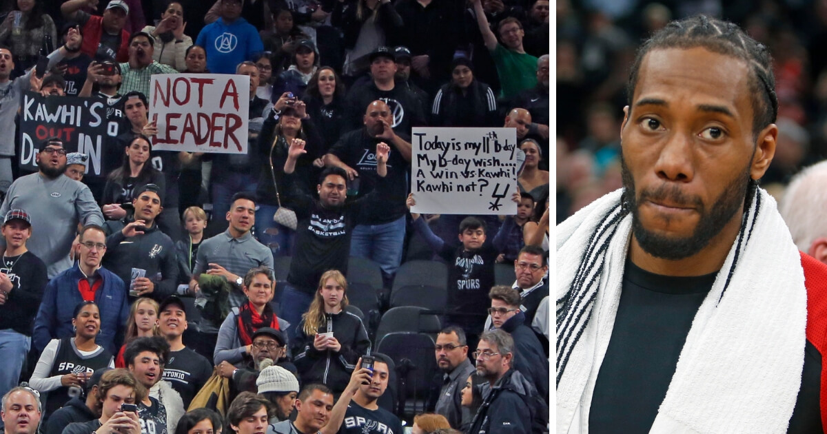 San Antonio fans hold up anti-Kawhi Leonard signs as Leonard, a former Spur now with the Toronto Raptors, leaves the floor at AT&T Center on Thursday.