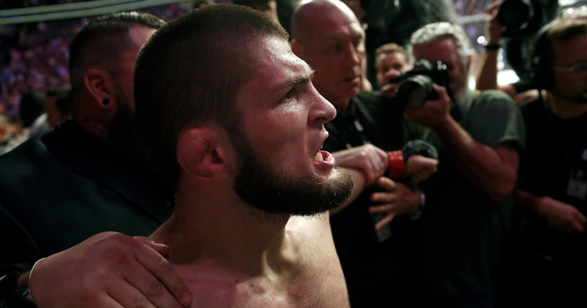 Khabib Nurmagomedov is held back outside of the cage after beating Conor McGregor in a lightweight title bout at UFC 229 in Las Vegas on Oct. 6, 2018.