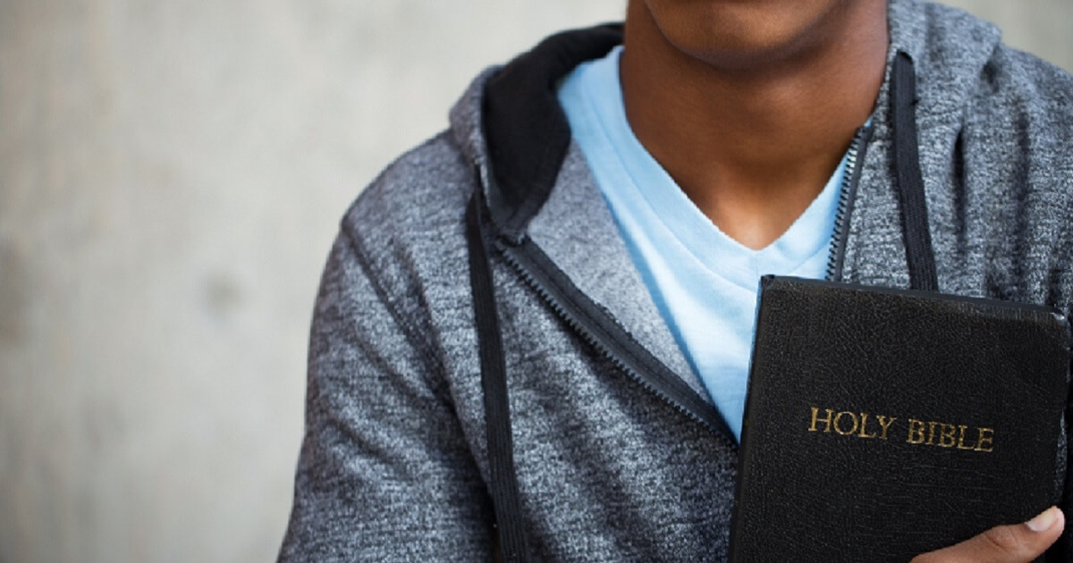 Young man holding Bible.