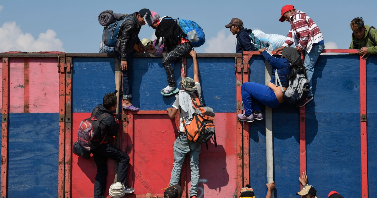 Migrant caravan men jumping over barrier