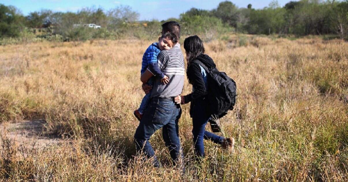 A migrant family crossing a field.