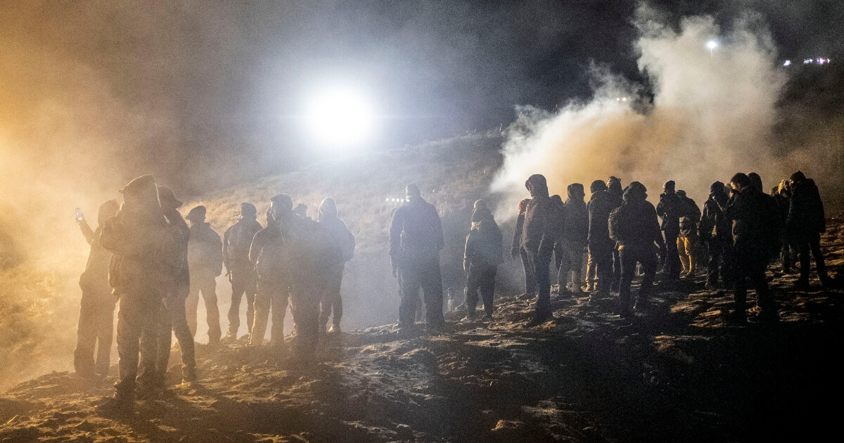 Central American migrants stand amid a cloud of tear gas after their attempt to illegally cross the U.S.-Mexico border near San Diego led to clashes with U.S. Border Patrol agents.
