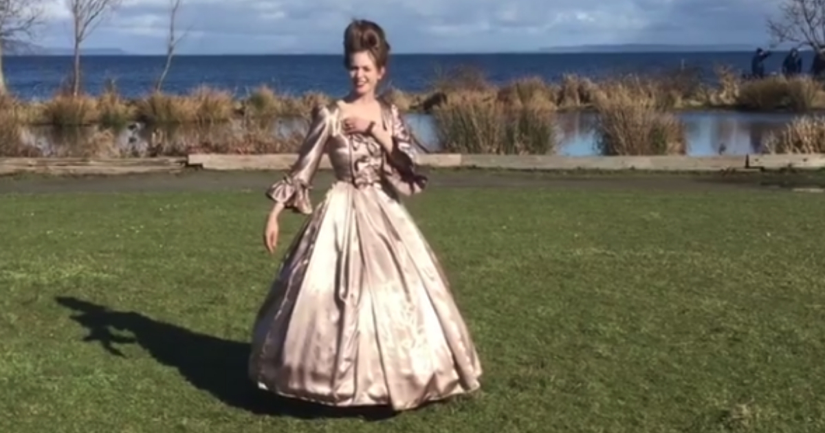 Woman stands in a ball gown.