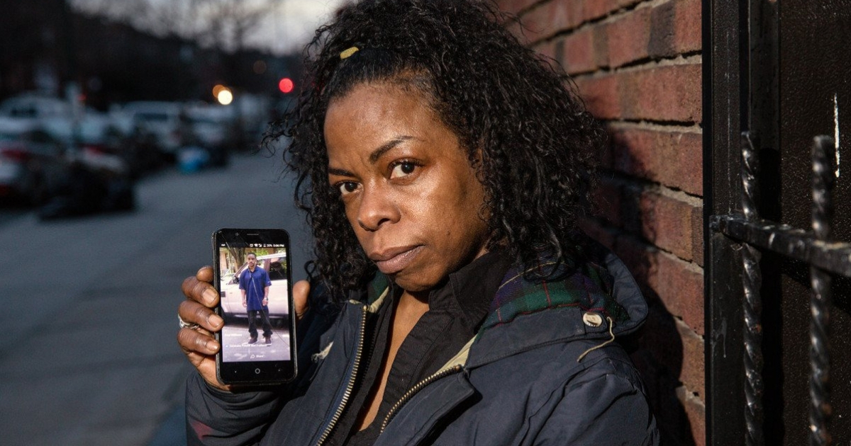 Woman holds a phone with a picture of her brother on it.