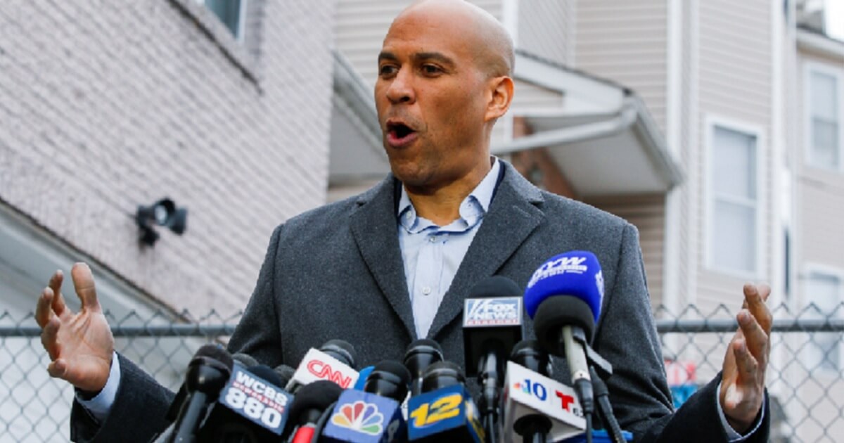 Sen. Cory Booker in front of a stand of microphones.