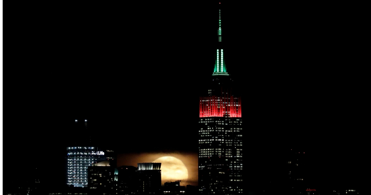 A full moon rises behind New York City near the Empire State Building.