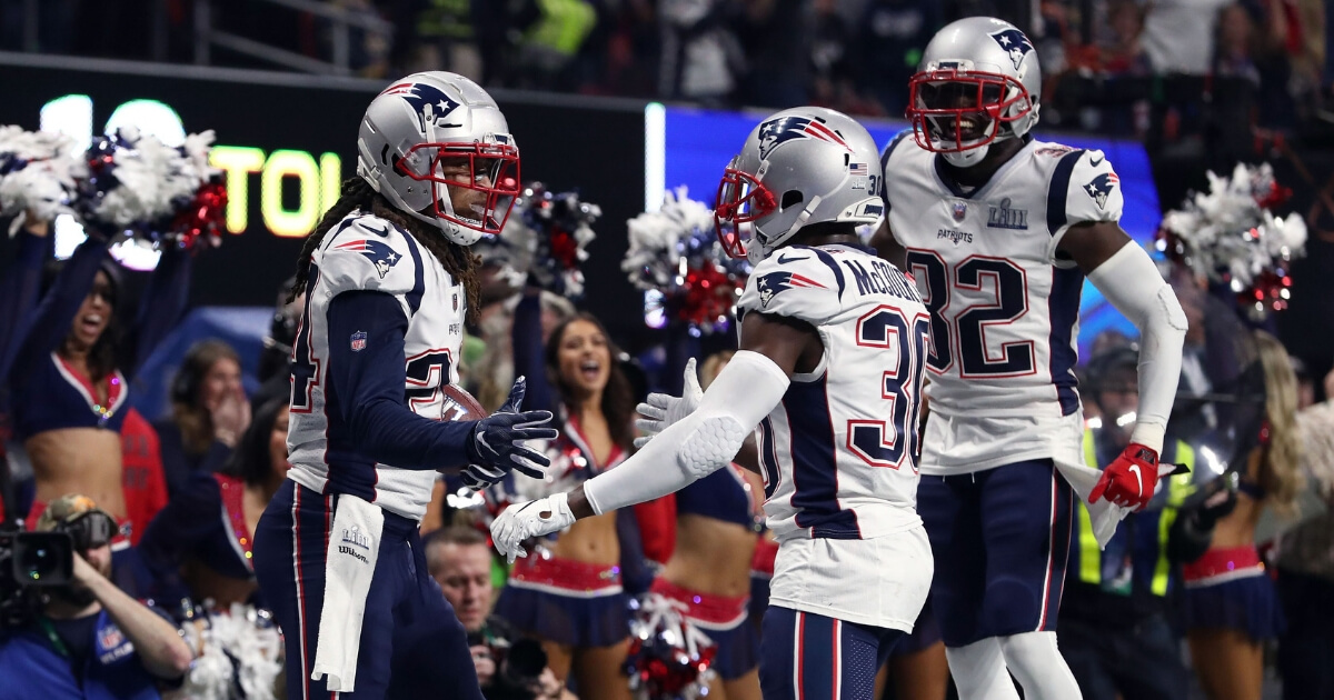Stephon Gilmore (No. 24) of the New England Patriots is congratulated by teammates Jason McCourty (30) and Devin McCourty (32) after his fourth-quarter interception Sunday against the Los Angeles Rams during Super Bowl LIII at Mercedes-Benz Stadium in Atlanta.