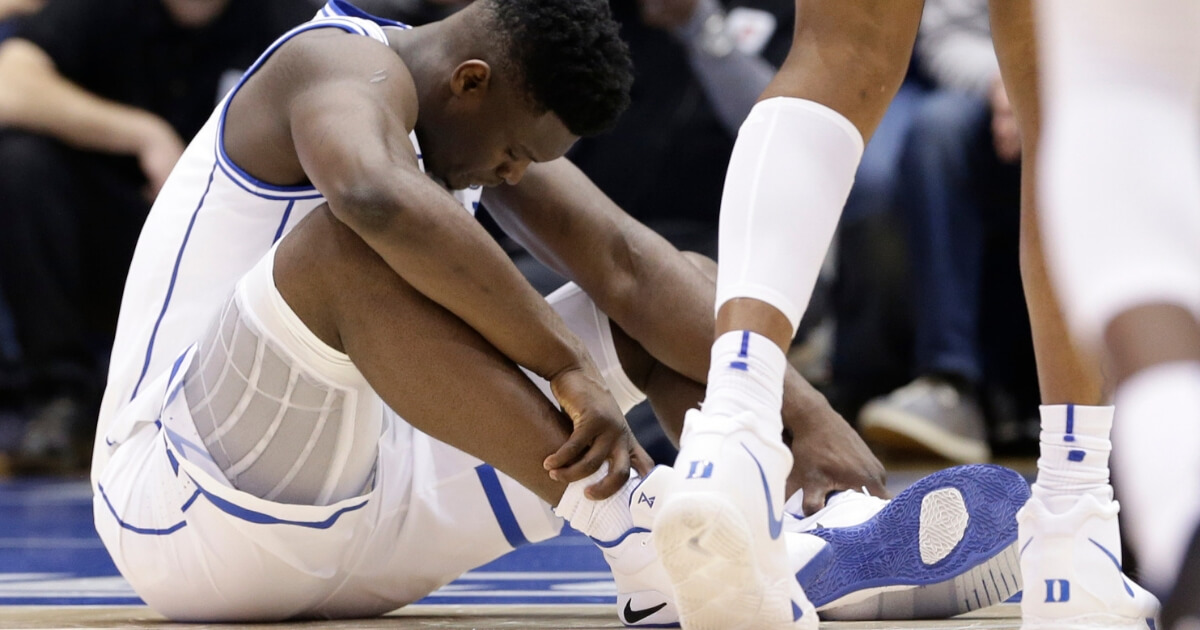 Duke's Zion Williamson sits on the floor looking at his busted Nike shoe during the Blue Devils' game against North Carolina on Wednesday.