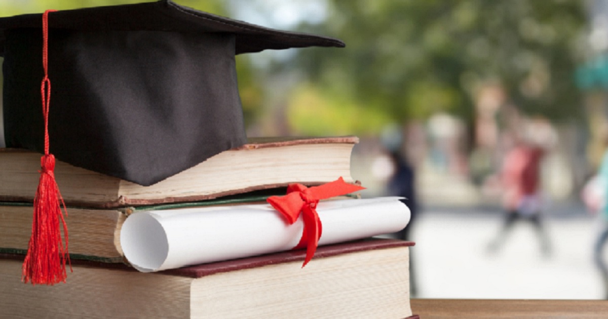 A graduation cap on books with a diploma.