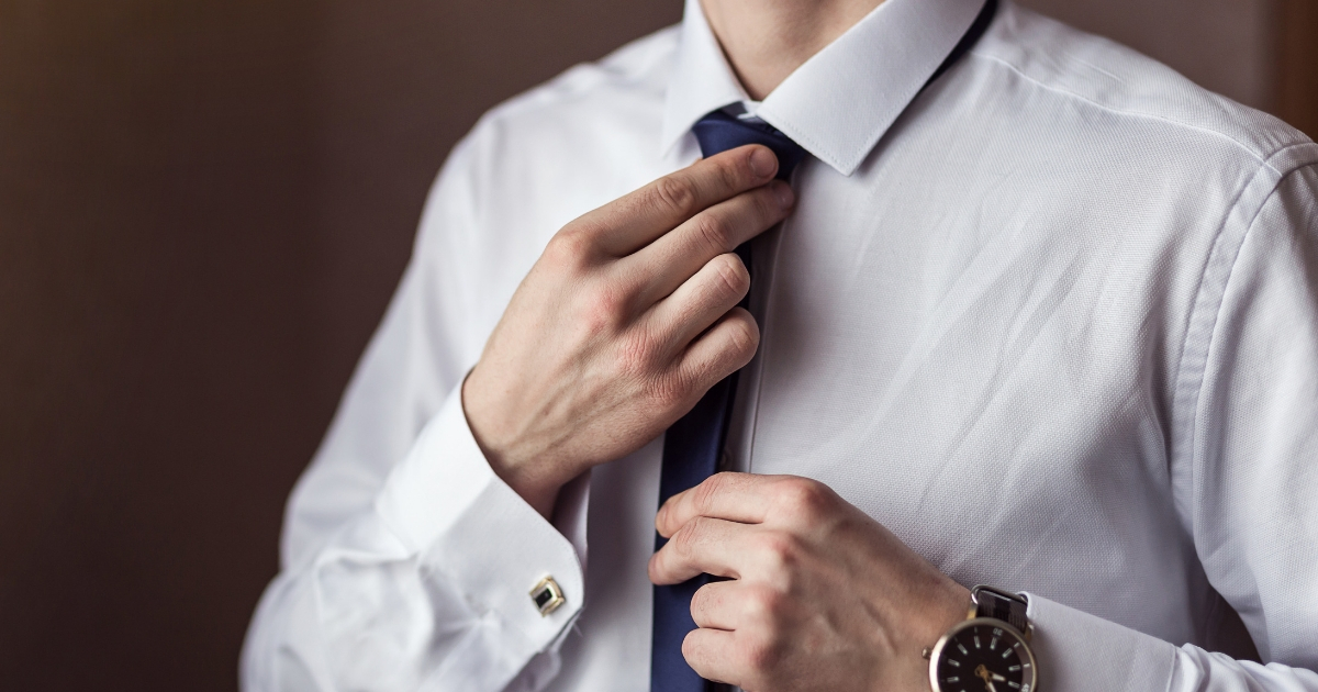 Man in shirt adjusting his tie.