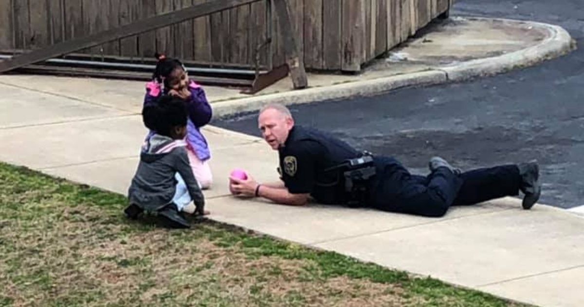 Police officer plays with dolls with young girls.