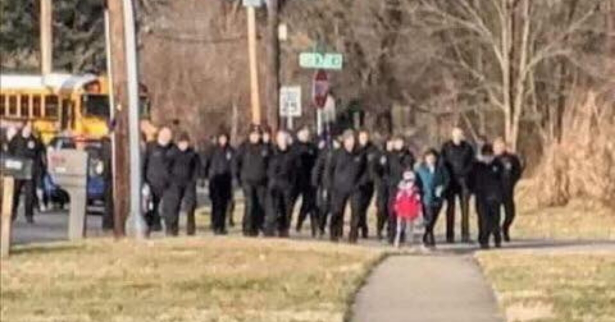 Group of police officers walking boy to school.