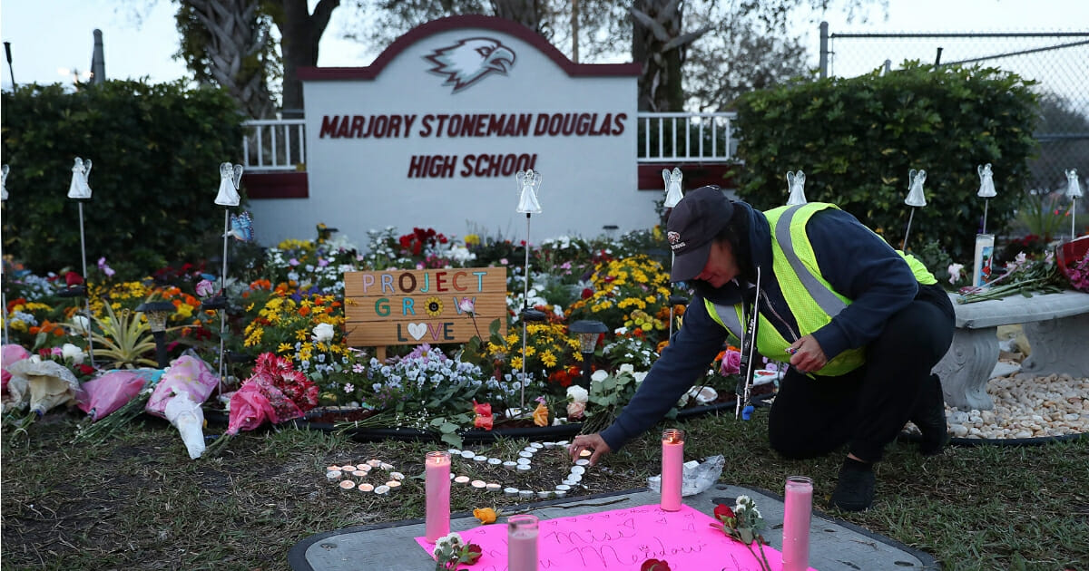 Wendy Behrend, a school crossing guard who was on duty one year ago when a shooter opened fire in Marjory Stoneman Douglas High School pays her respects at a memorial setup for those killed on in Parkland, Florida.