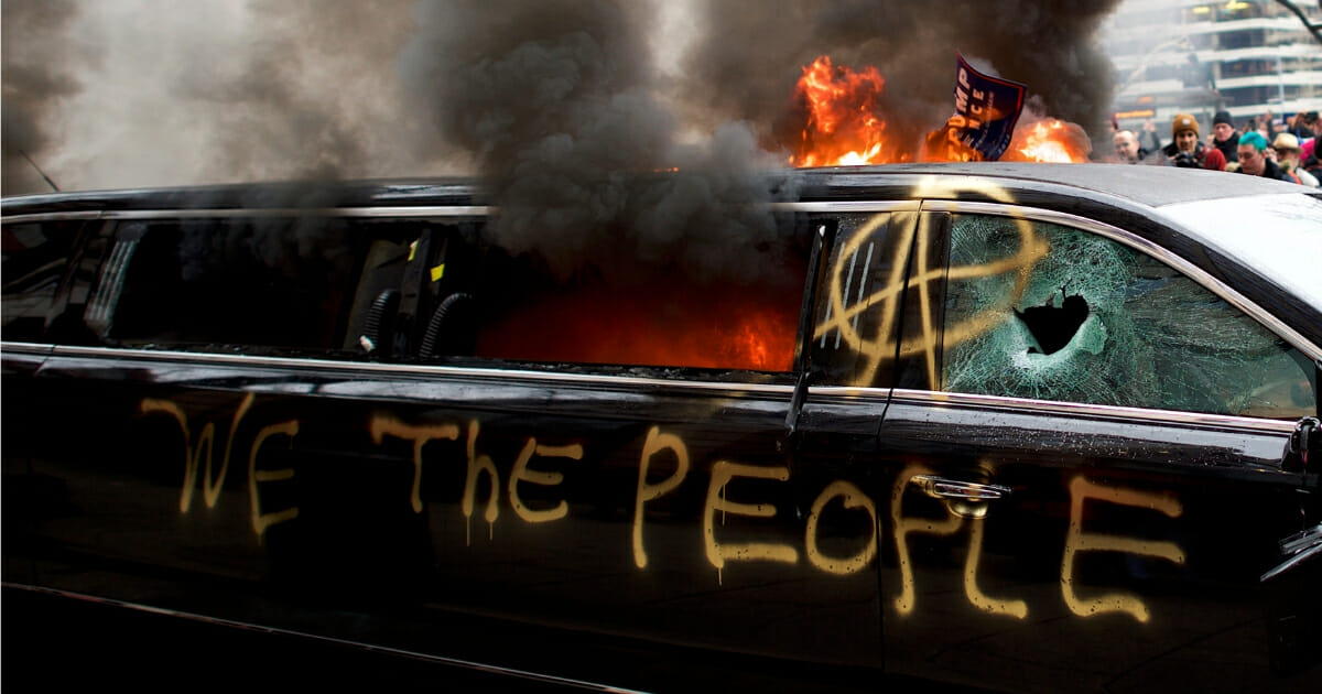 A limousine is set aflame with the graffiti of 'We the People' spray painted on the side after the inauguration of Donald Trump.