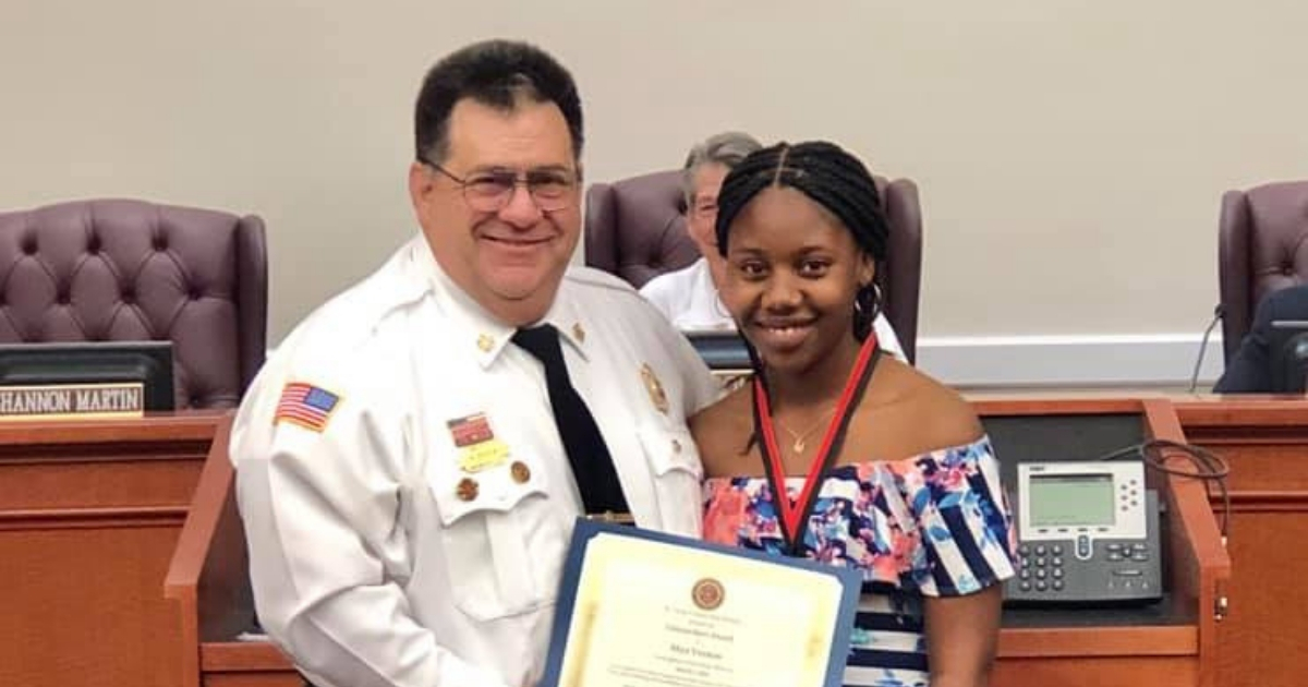 Fire chief gives young girl an award.