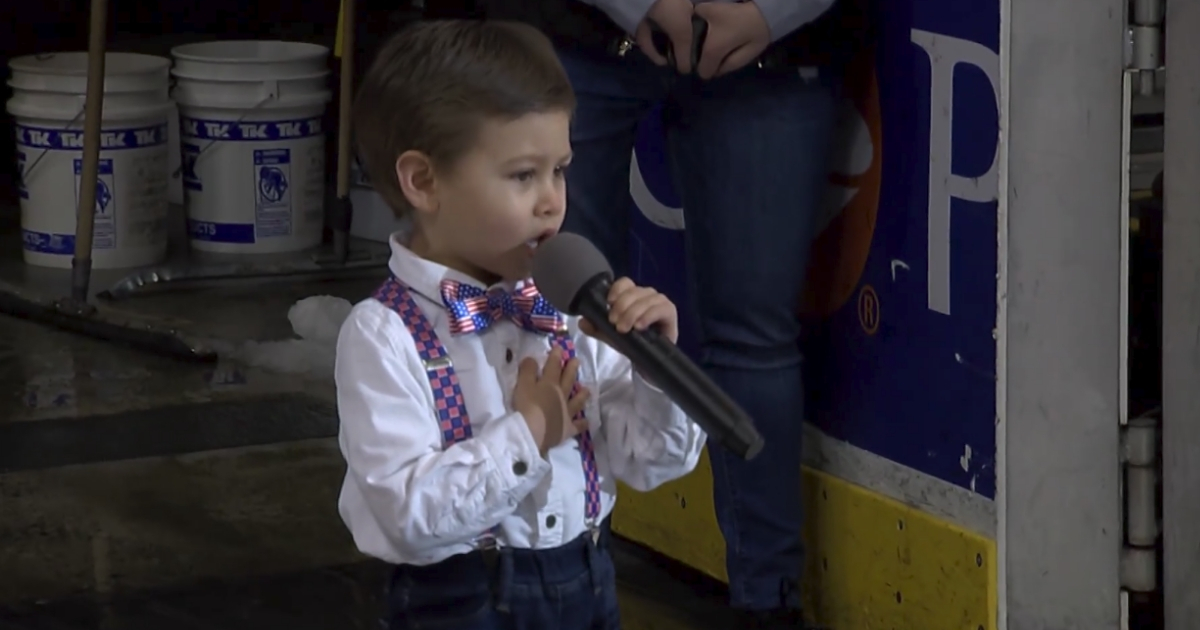 Little boy singing at a hockey game.