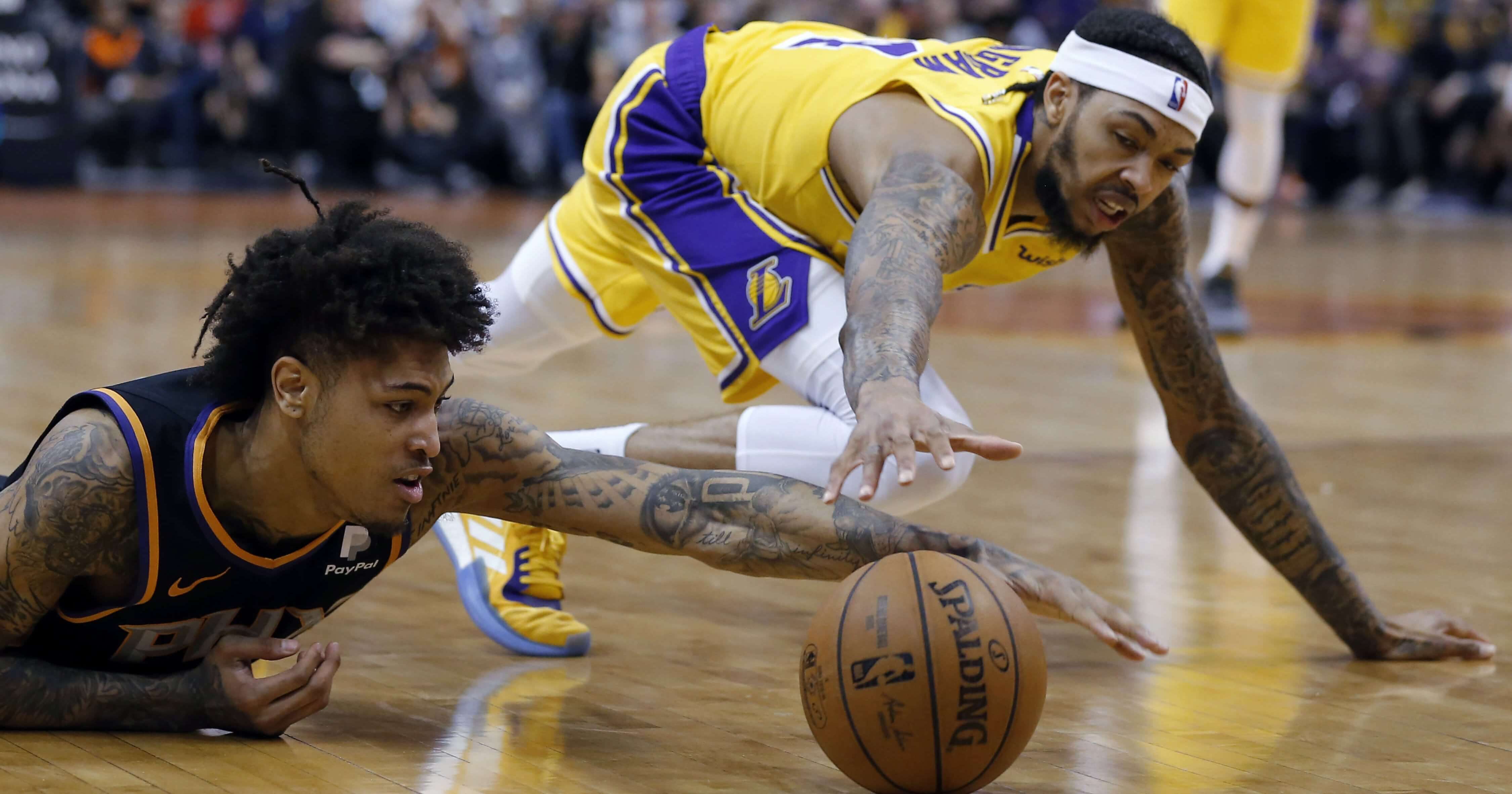 Phoenix Suns forward Kelly Oubre Jr., left, dives for a loose ball in front of Los Angeles Lakers forward Brandon Ingram during the first half of an NBA basketball game Saturday, Mar. 2, 2019, in Phoenix.