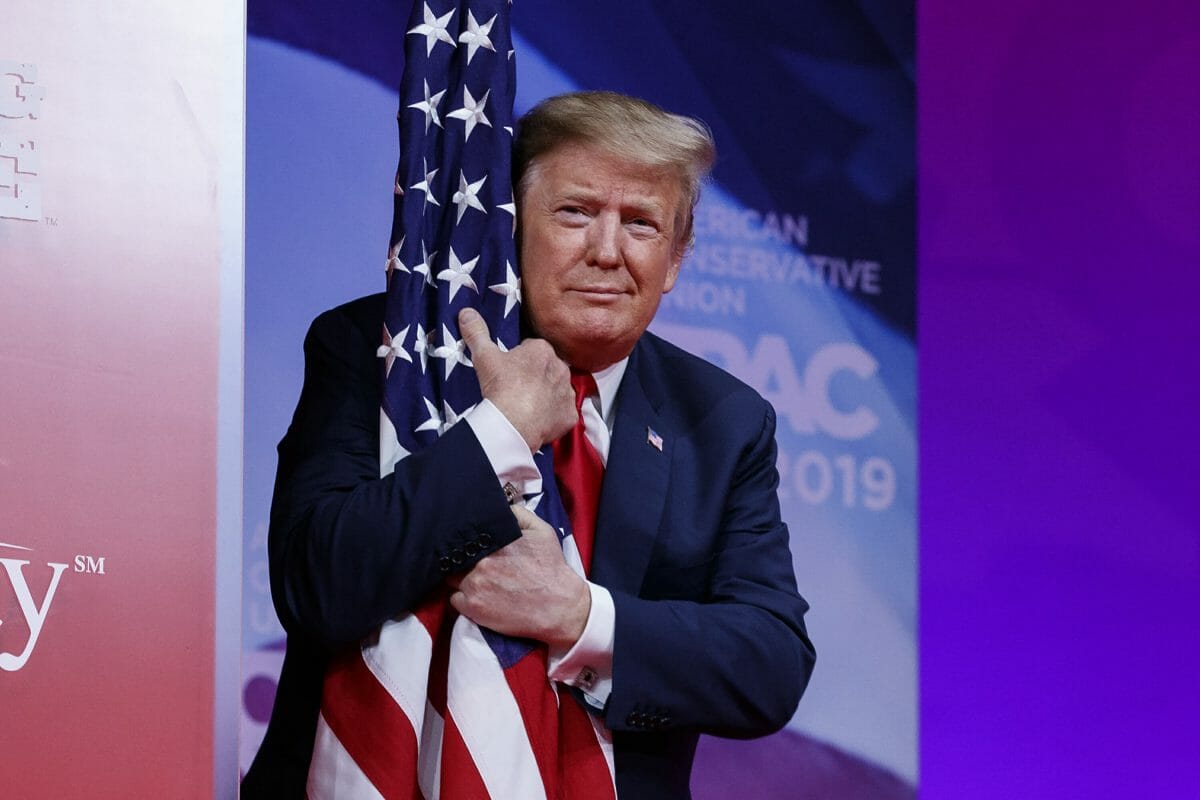 President Donald Trump hugs the American flag as he arrives to speak at Conservative Political Action Conference, CPAC 2019.