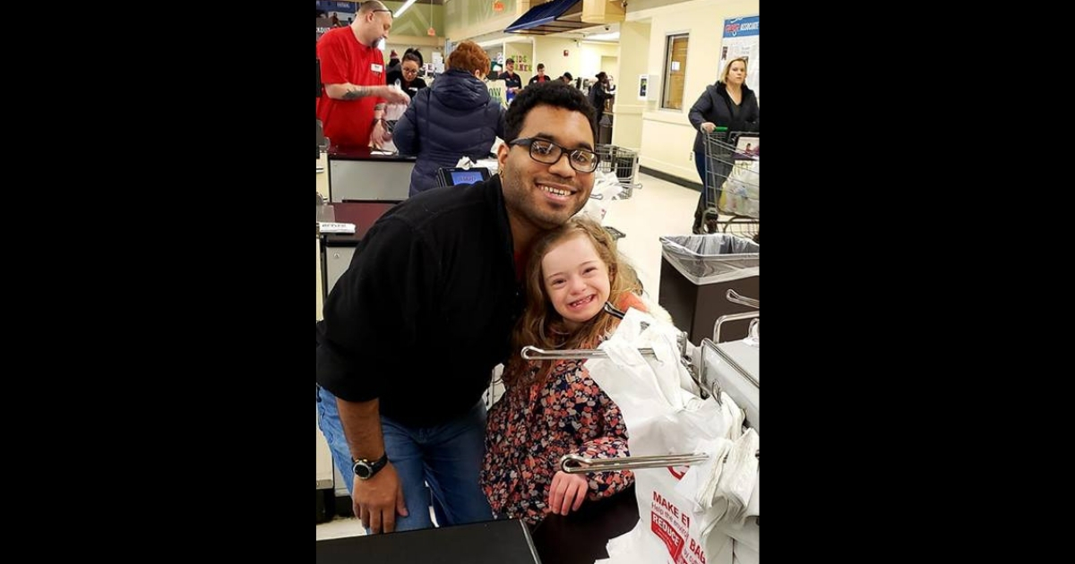 Little girl smiles next to a cashier who let her help bag groceries.