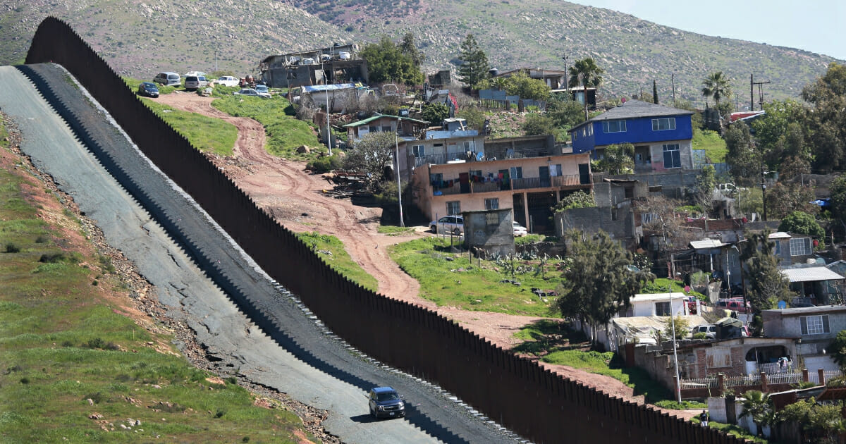 A car drives along the U.S.-Mexico border fence on Feb. 22, 2019, in Otay Mesa, California.