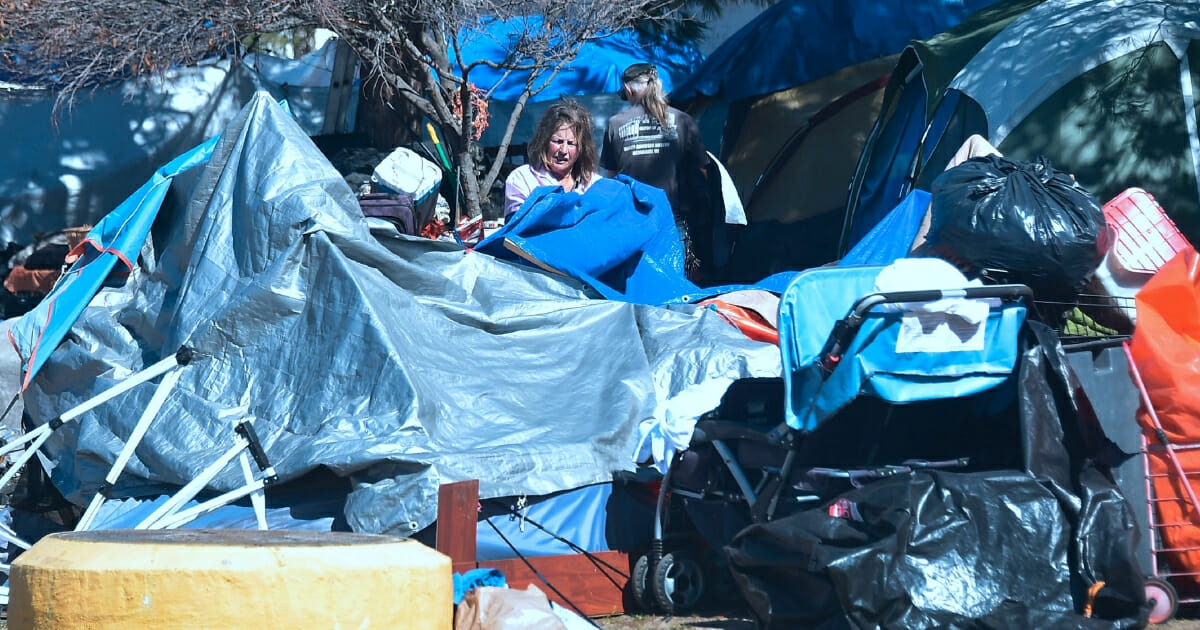 A homeless woman packs up her tent and belongings at the homeless encampment beside the Santa Ana River in Anaheim, California, on February 20, 2018.