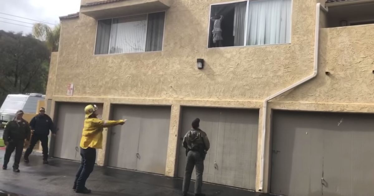 Deputy stands beneath window little girl is leaning out of