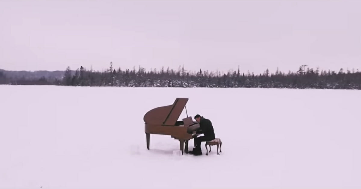 Man playing piano in the middle of a lake.