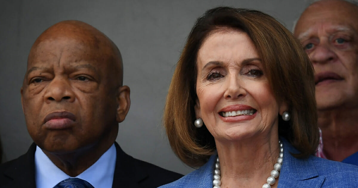 Democrat Rep. John Lewis, left, stands with then-House Minority Leader Nancy Pelosi, right, who's since been elected House speaker, during a rally to support new anti-poverty legislation in South Central Los Angeles, California on April 9, 2017.
