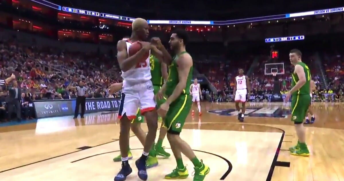 Ehab Amin, right, of the Oregon Ducks flopped after a tap from Virginia's Mamadi Diakite.