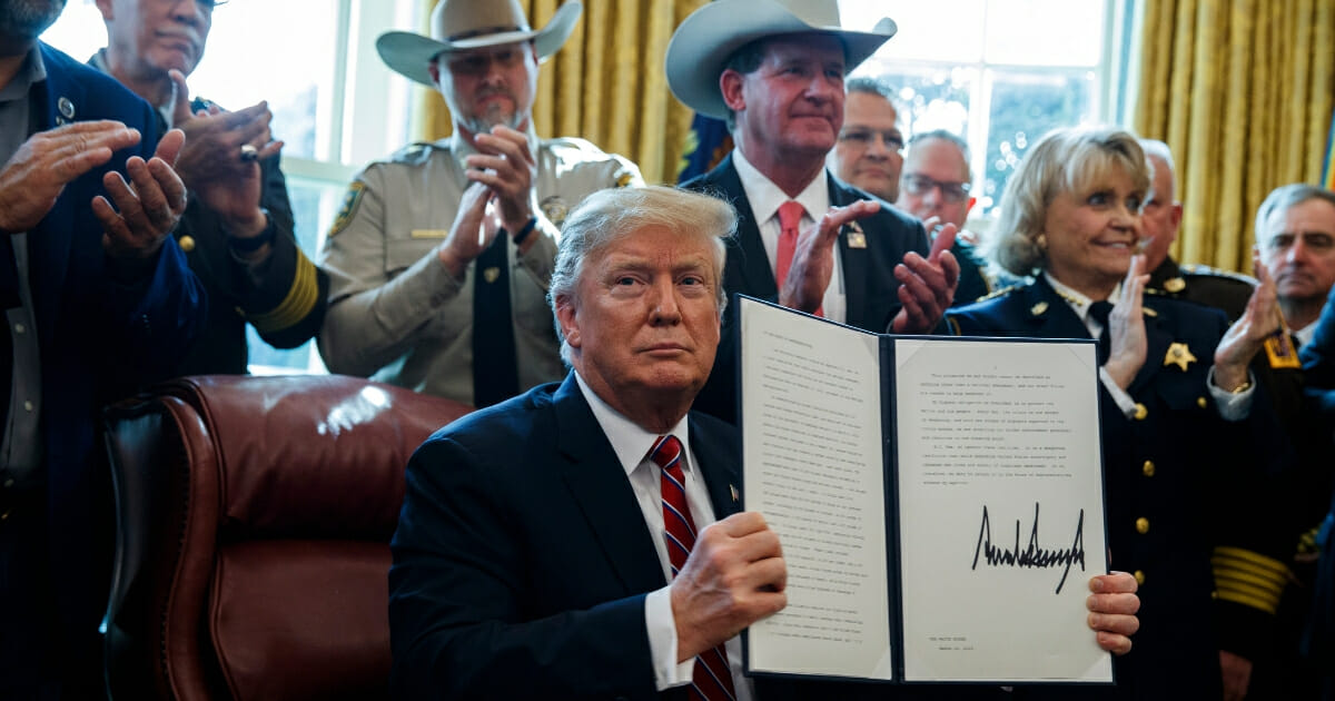 Law enforcement officials applaud after President Donald Trump signs the first veto of his presidency in the Oval Office of the White House on March 15, 2019, in Washington.