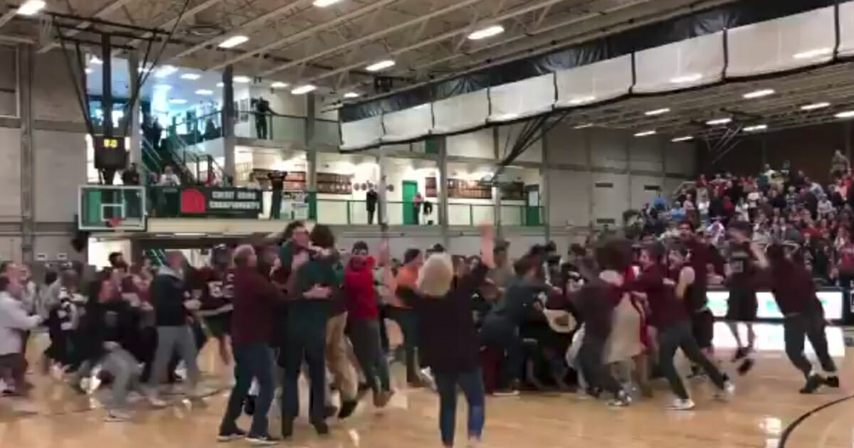 Fans storm the court after Pat Shea of East Greenwich High School made a buzzer-beater to win the Rhode Island Division II state championship in boys' basketball.
