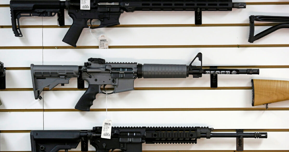 Rifles for sale at a gun store include a Ruger AR-15 semi-automatic rifle, center.