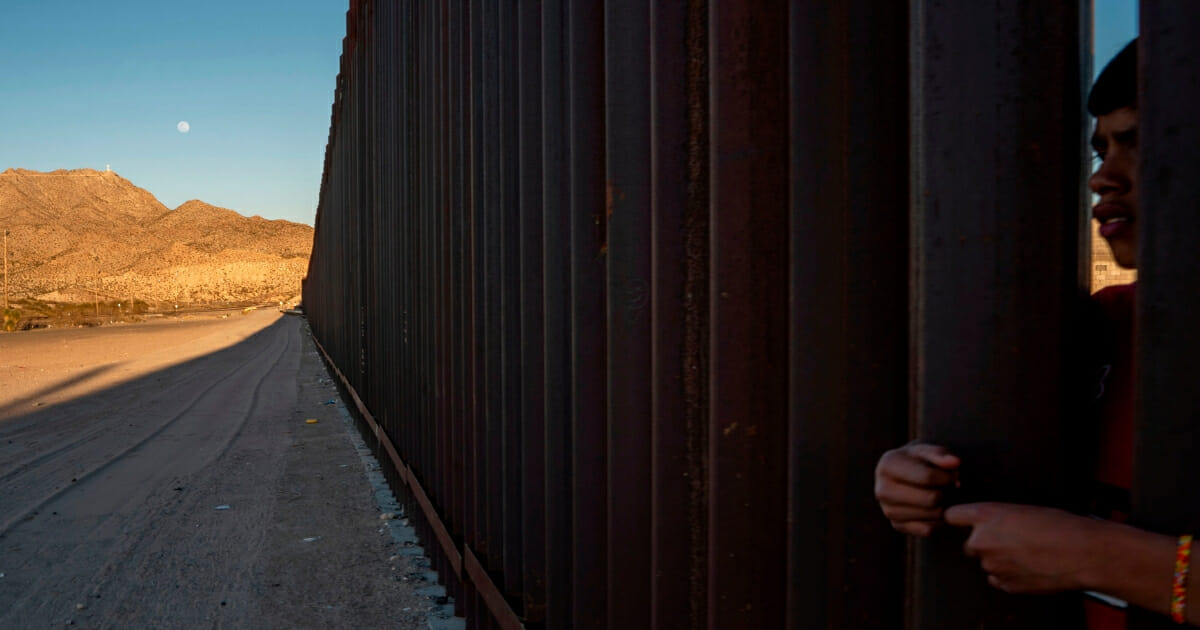A boy peers through the metal fencing on the southern border in Anapra, New Mexico, on March 19, 2019.