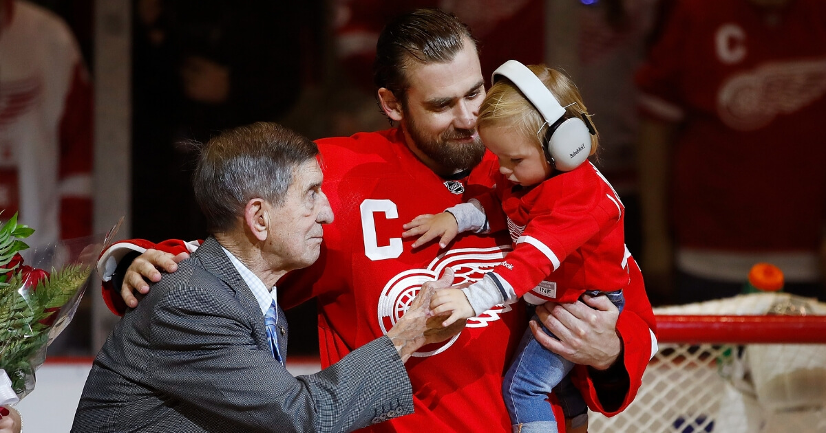 Henrik Zetterberg, center, of the Detroit Red Wings, his son Love and Red Wings legend Ted Lindsay during presentation to honor his 1000th NHL game prior to a game against the New Jersey Devils at Joe Louis Arena on April 9, 2017 in Detroit.