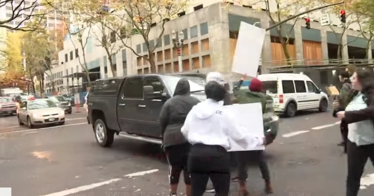 The car of Mark Dickerson driving through a line of protesters.