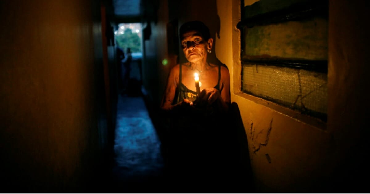 A Venezuelan woman uses a candle to navigate in through her home in the Santa Cruz of the East neighborhood of Caracas during the country's huge power outage on March 14.