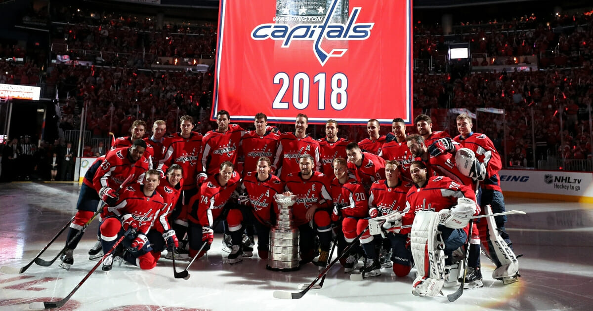 The Washington Capitals pose for a photo before their 2018 Stanley Cup Championship banner rises to the rafters at Capital One Arena on Oct. 3, 2018.
