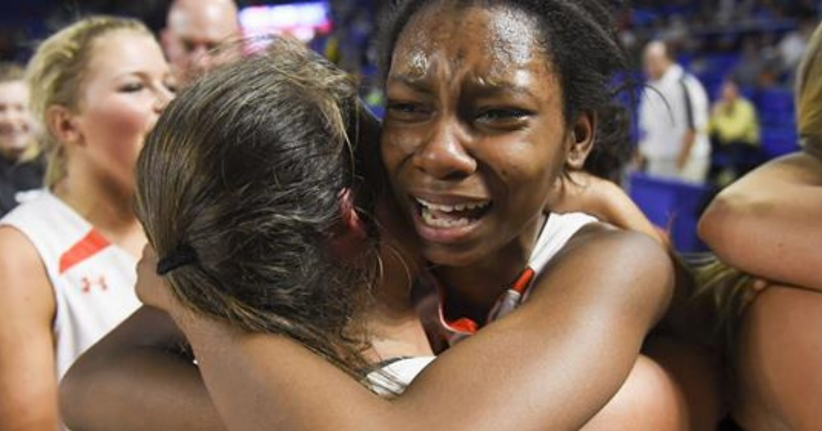 Two basketball players share an emotional hug.