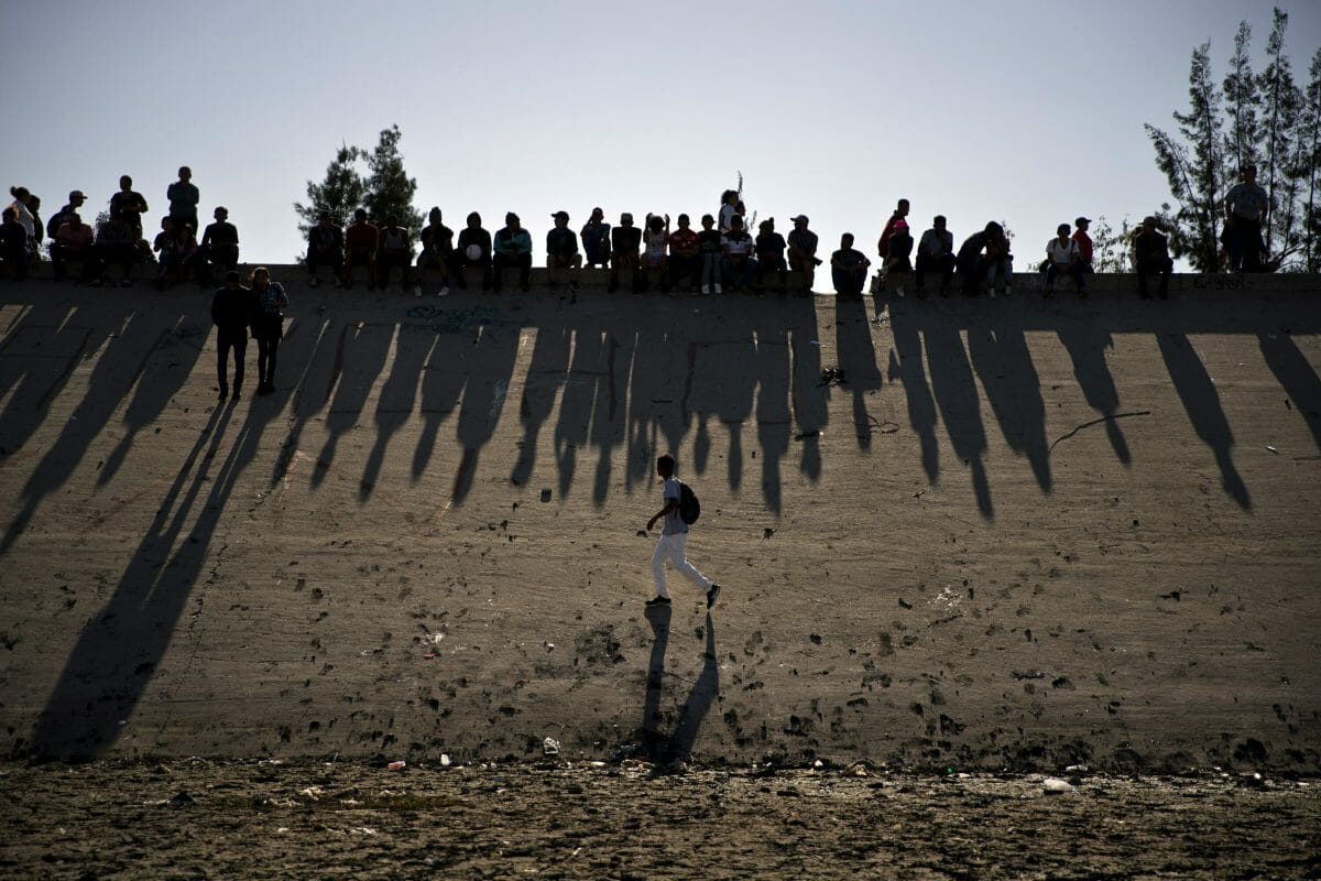 Migrants near the Chaparral border crossing watch clashes with U.S. border agents, seen from Tijuana, Mexico.