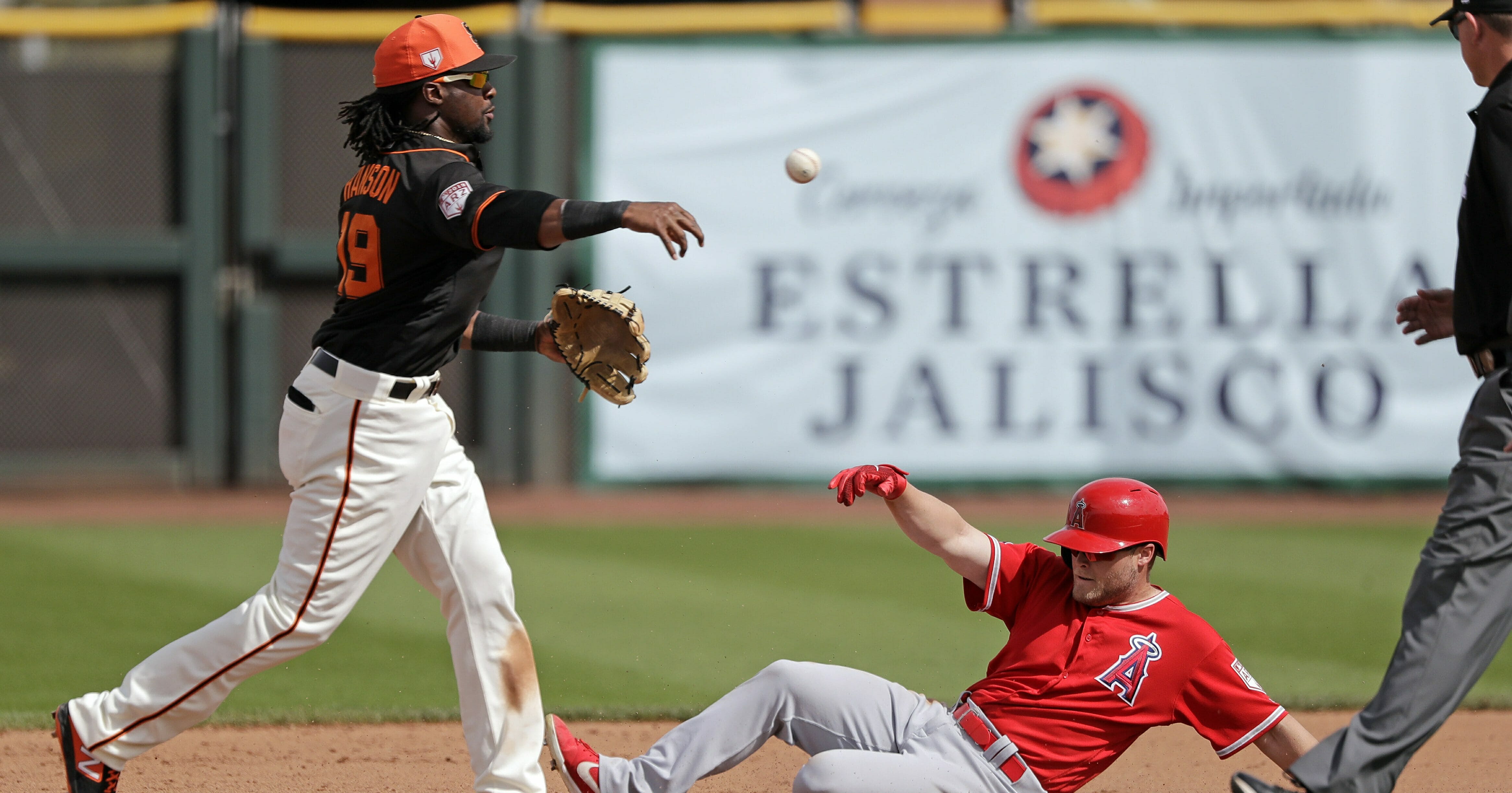 San Francisco Giants shortstop Alen Hanson, left, throws to first base after forcing out Los Angeles Angels' Brennon Lund at second base in the fifth inning of a spring training baseball game Friday, Mar. 15, 2019, in Phoenix.