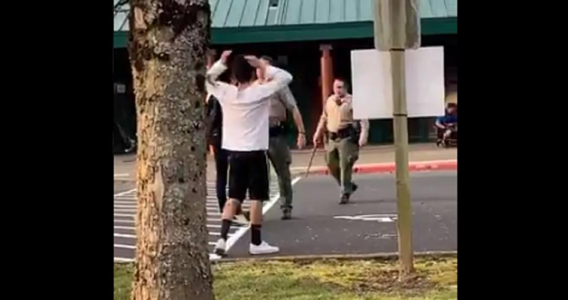 A Clark County, Washington, sheriff's deputy confronts an unruly crowd Friday at a middle school, where a disturbance turned into a near riot.