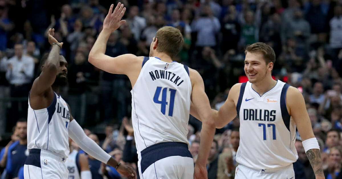 Dirk Nowitzki of the Dallas Mavericks celebrates with Tim Hardaway Jr. and Luka Doncic after scoring a basket against Kenrich Williams of the New Orleans Pelicans to become the sixth all-time leading scorer in the NBA at American Airlines Center on Mar. 18, 2019 in Dallas.