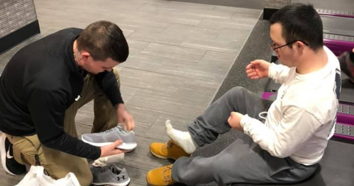 Gym manager puts shoes on man with Down syndrome.