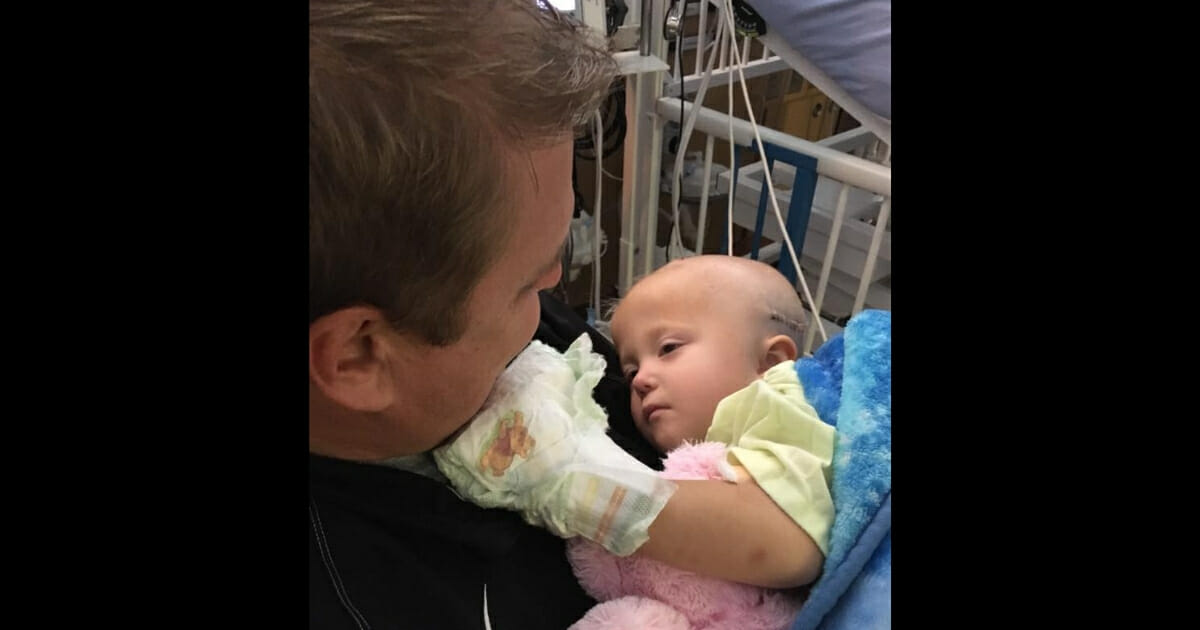 A dad holds his daughter in the hospital.
