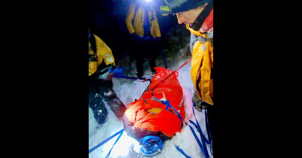 Skier in a heated sled rescued from a snowy mountain.